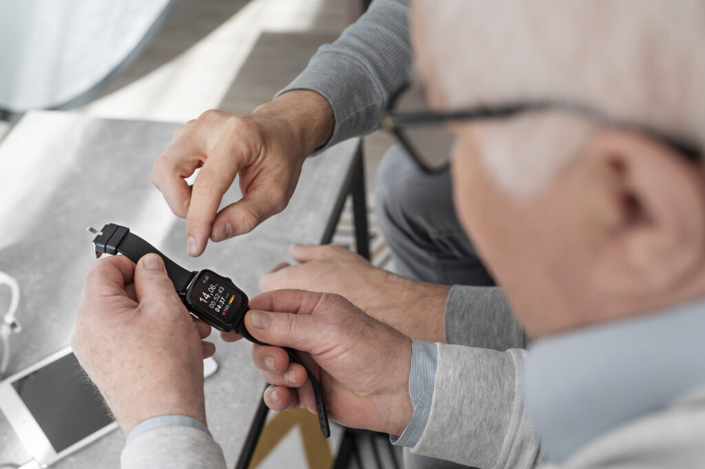 Pflegekraft hilft einem Senior beim Einstellen einer Smartwatch.